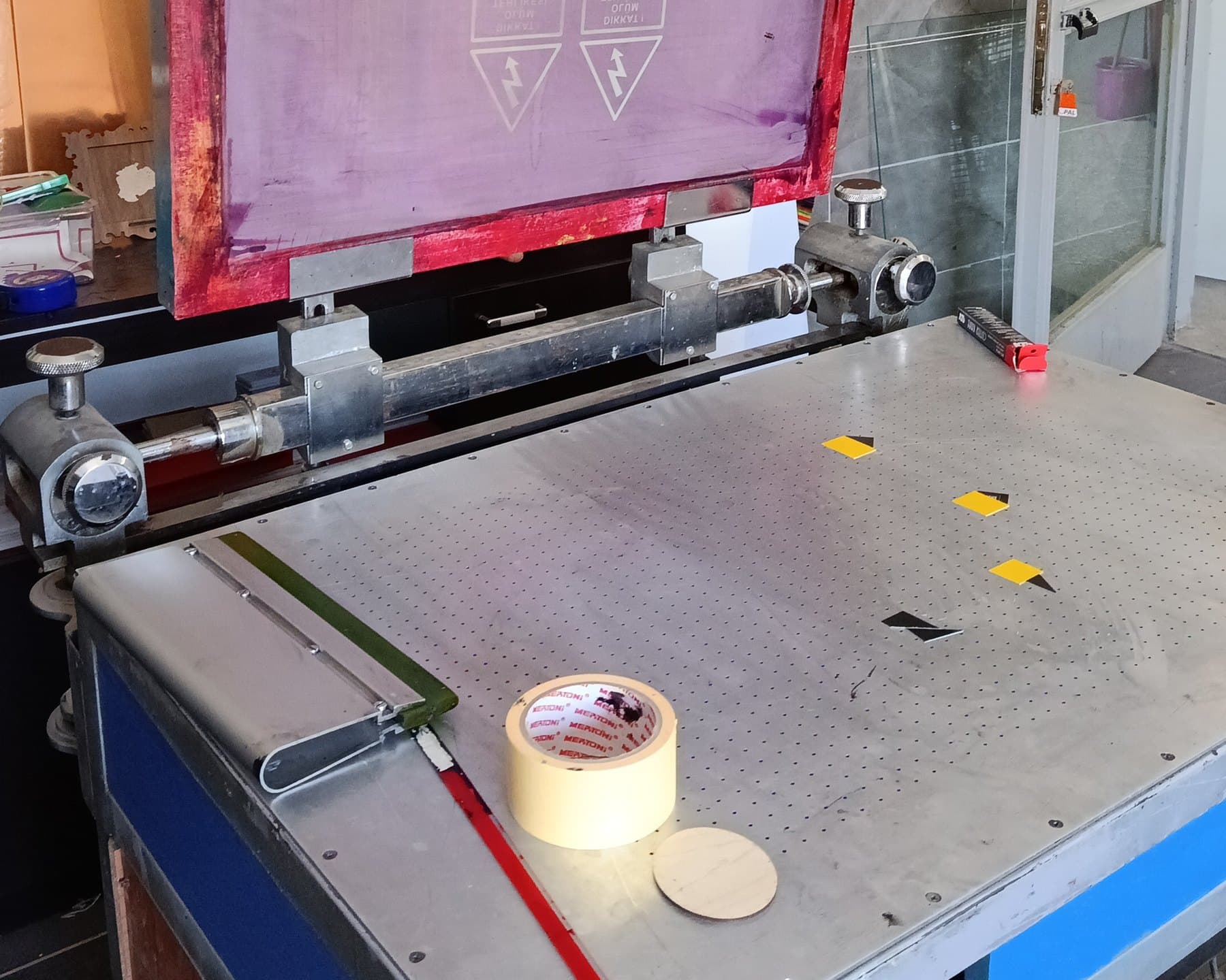 Serigrafi baskı tezgâhı — delikli vakum masası, sarı hizalama bantları, ragle ve menteşeli elek çerçevesi | Divan Etiket Ankara